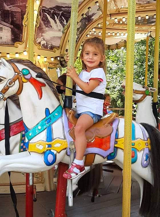 Emma a rejoint le concours — aidez-le/la à gagner de superbes lots ! amusement_park, amusement_ride, carousel, child, event, fair, fun, horse, horse_tack, joy, leisure, mammal, nonbuilding_structure, outdoor_recreation, person, photograph, playground, recreation, smile, snapshot