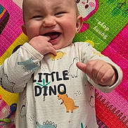 Lowen participe au concours pour gagner de l'argent avec cette photo : baby, child, smiling, dinosaur, onesie, playmat, colorful, happy, cute, infant, fingers, laughing, indoors, toy, patterned_clothing, cheerful, closeup, face, head, playtime