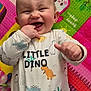 baby, child, smiling, dinosaur, onesie, playmat, colorful, happy, cute, infant, fingers, laughing, indoors, toy, patterned_clothing, cheerful, closeup, face, head, playtime