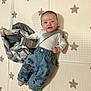 baby, child, infant, playmat, stars, denim_pants, colorful, patterned, bag, white_shirt, strap, floor, cute, smiling, indoor, young_child, clothing, person, portrait, lying_down