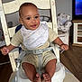 baby, child, high_chair, bib, smile, face, hands, feet, knit_clothing, wooden_chair, indoor, flooring, television, furniture, room, safety_strap, expression, comfort, infant, cute