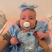 Luna a rejoint le concours — aidez-le/la à gagner de superbes lots ! baby, infant, pacifier, blue_dress, headband, bow, tattoo, holding_hands, cute, portrait, child, indoors, soft_light, closeup, person, newborn, clothing, fabric, decorative, baby_girl