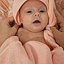 baby, infant, pink_towel, animal_hood, blanket, hands, skin, face, eyes, mouth, bed, patterned_bed_sheet, soft_texture, cute, wrapped, newborn, portrait, indoor, comfort, care