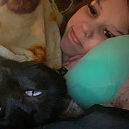 Iris And Karma is registered to the contest to win money with this photo: person, dog, black_dog, blanket, pillow, indoor, resting, smile, face, cozy, snuggle, closeup, human, pet, lying_down, relaxed, comfort, warm, bed, casual