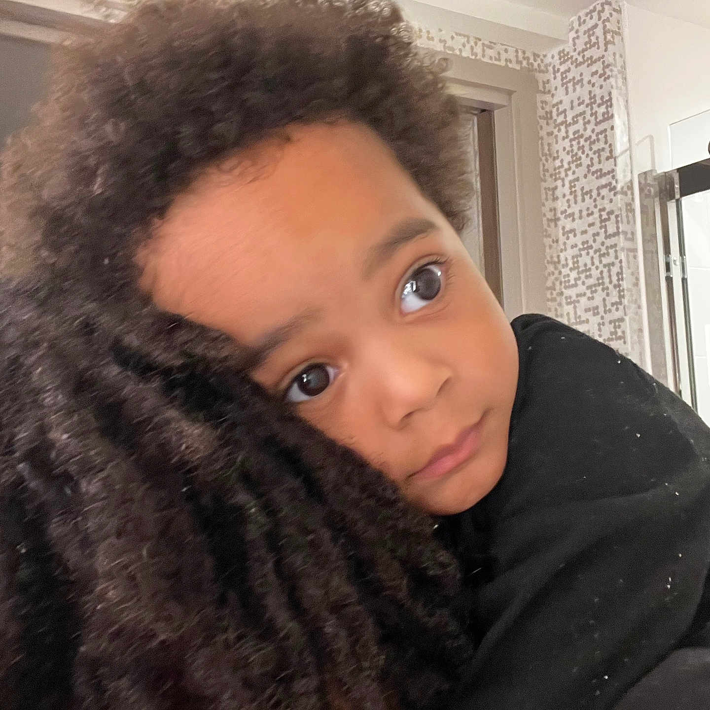Asaiah is registered to the contest to win money with this photo: affection, black_clothing, caring, child, close_up, comfort, curly_hair, expression, eyes, face, hair, hug, human, indoor, person, portrait, skin, tile_wall, window, young