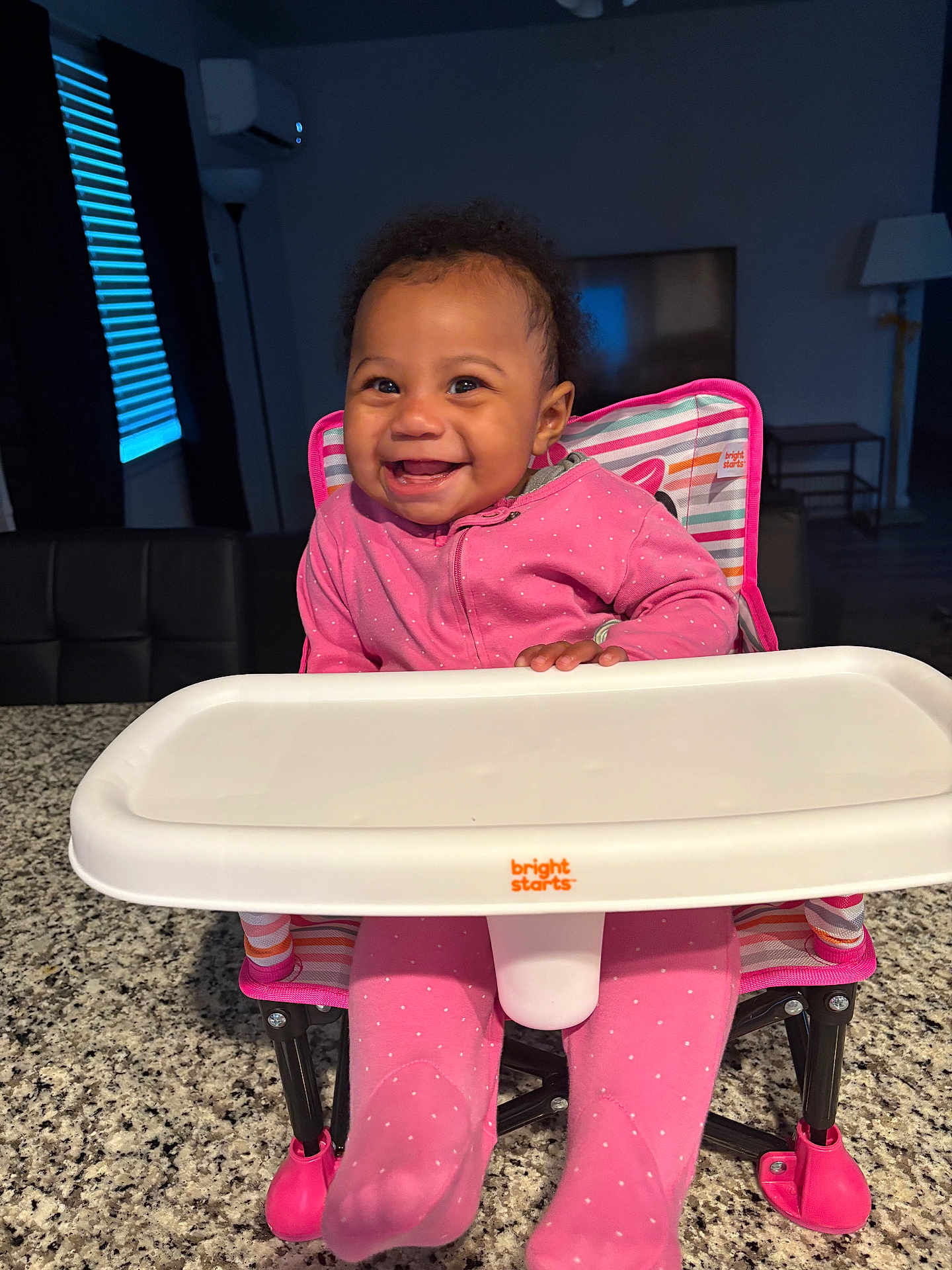 Akiriya joined the competition — help win amazing prizes! baby, child, cute, face, floor_lamp, footwear, furniture, granite_countertop, happy, high_chair, home, indoor, infant, person, pink_clothing, seat, smiling, table, television, window