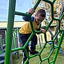 Jacob is registered to the contest to win money with this photo: child, boy, playground, climbing_frame, green, outdoor, daylight, sportswear, activity, young, tree, blue_sky, building, footwear, sneakers, focus, play, metal, exercise, fun