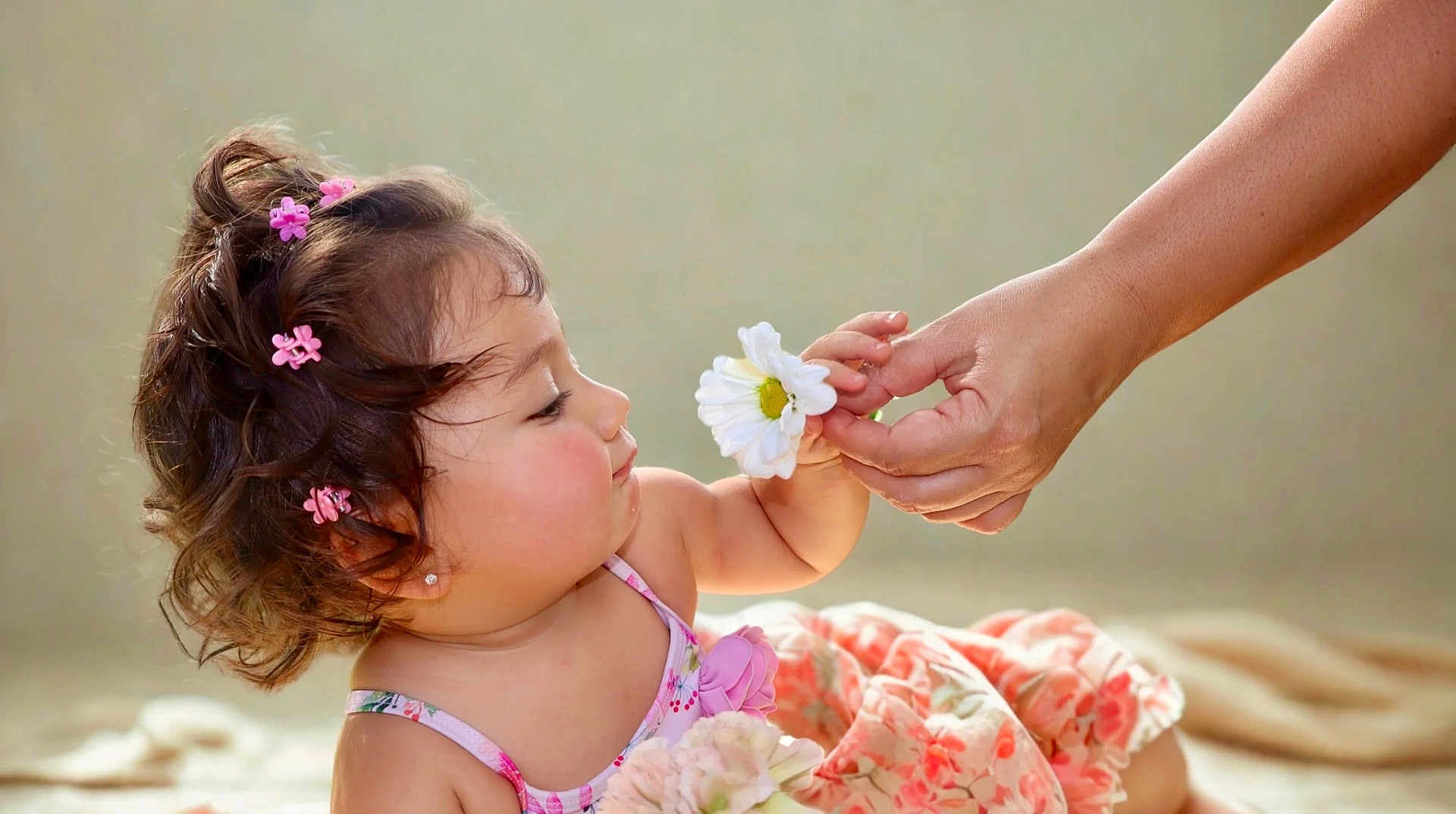 Alana joined the competition — help win amazing prizes! child, toddler, flower, hand, pink_clips, curly_hair, dress, floral_pattern, skin, face, person, innocence, interaction, soft_light, pastel_colors, baby, earring, indoor, closeup, gentle