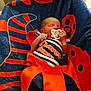 Celine is registered to the contest to win money with this photo: baby, newborn, pacifier, blanket, clothing, denver_broncos, orange, blue, sleeping, infant, person, chair, indoor, soft_lighting, resting, cute, sports_team, nursery, portrait, cozy