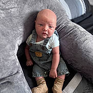 Louie joined the competition — help win amazing prizes! baby, infant, denim_overalls, socks, bear_design, cushion, gray, soft, seated, looking_at_camera, cute, child, indoor, portrait, clothing, skin, face, head, newborn, small