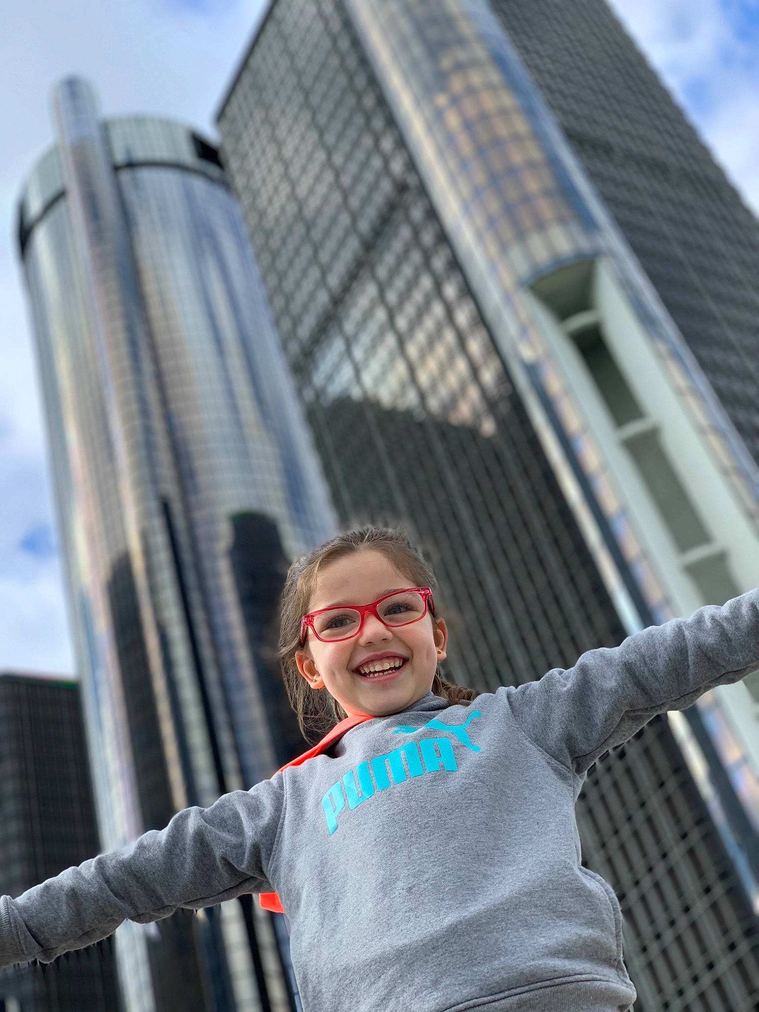 Selena joined the competition — help win amazing prizes! building, city, condominium, daytime, eyewear, facade, gesture, happy, joy, leisure, person, sky, skyscraper, sleeve, smile, standing, street, street_fashion, t_shirt, tower