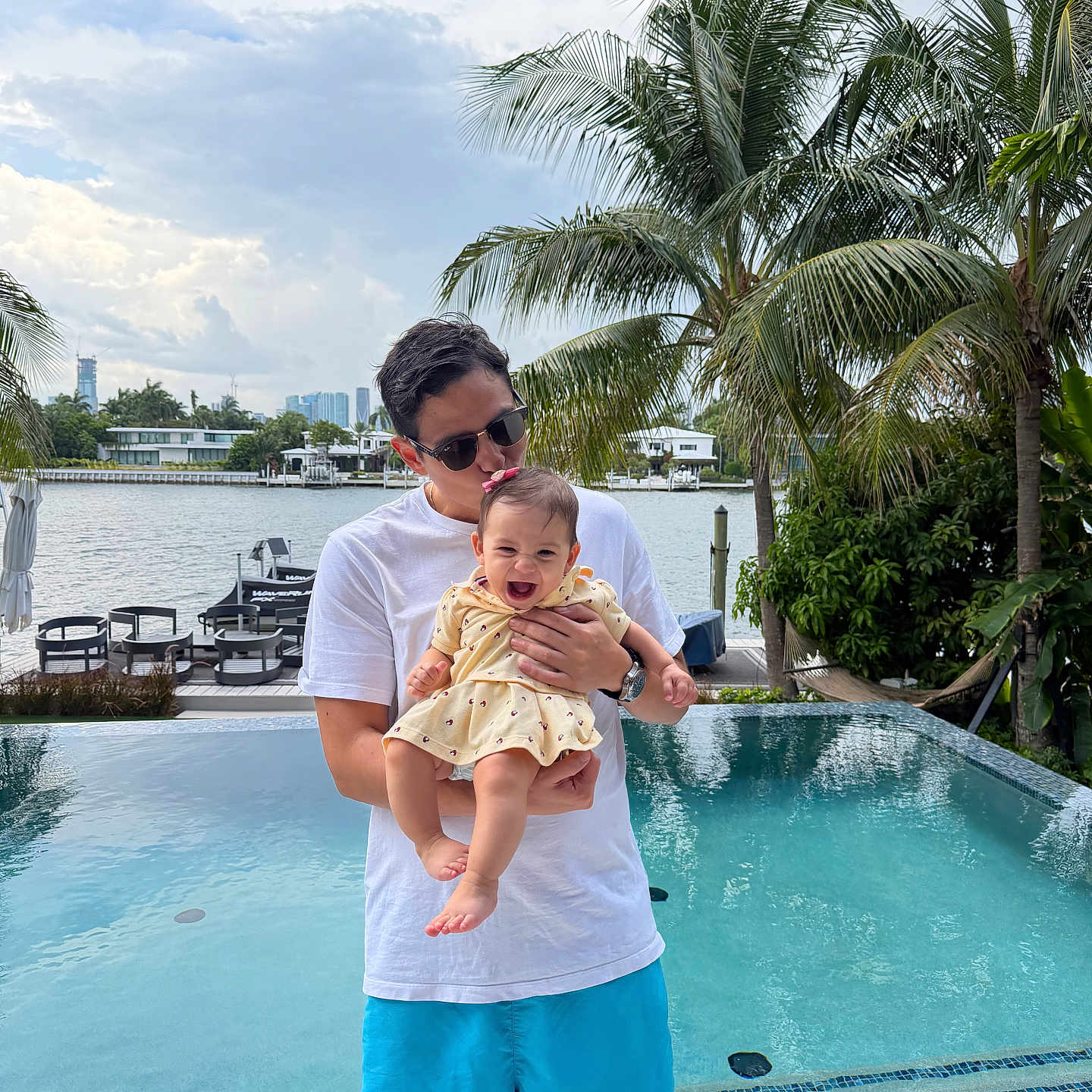 Zoe Mariana joined the competition — help win amazing prizes! baby, man, pool, water, palm_tree, outdoor, smile, sunglasses, dress, shorts, holding, nature, sky, clouds, vacation, happy, family, summer, tropical, portrait