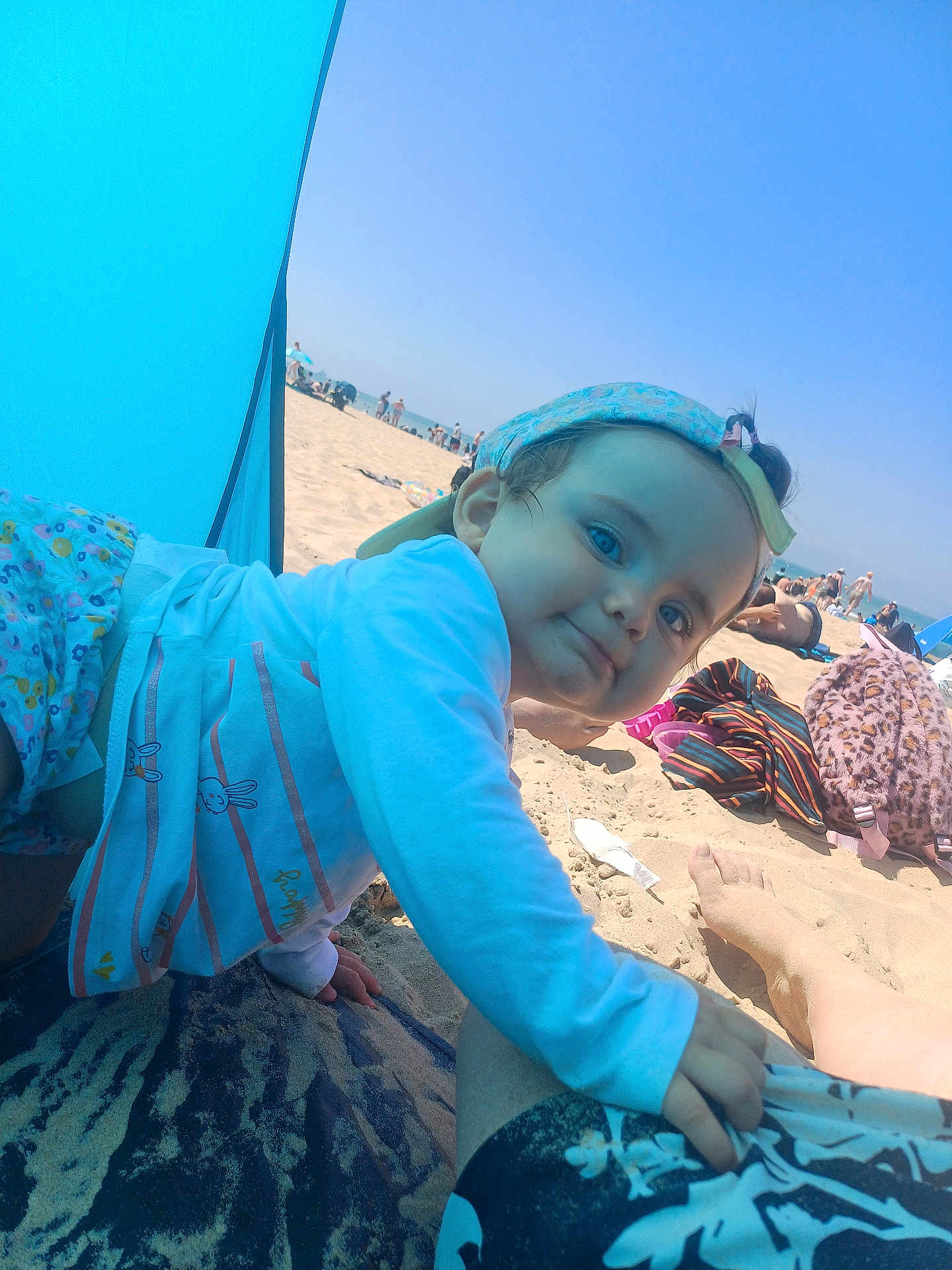 Lucy a rejoint le concours — aidez-le/la à gagner de superbes lots ! beach, blue_sky, cap, child, clothing, foot, holiday, mat, outdoor, pattern, people, playful, relaxation, sand, smiling, summer, sunlight, sunshade, toddler, vacation