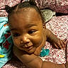 baby, child, twin_buns, blanket, towel, pacifier, smiling, curious, indoors, closeup, skin, face, hand, lying_down, cute, infant, colorful, patterned, soft_lighting, warmth