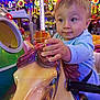 émilien participe au concours pour gagner de l'argent avec cette photo : amusement_park, carnival, carousel, child, clothing, colorful, entertainment, face, fun, hand, happy, horse, indoor, lights, person, playful, ride, seat, toddler, toy