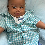 Dennis joined the competition — help win amazing prizes! baby, infant, child, blue_blanket, checkered_shirt, car_print, smiling, cute, soft_texture, portrait, casual_clothing, lying_down, indoors, happy, person, young_child, short_hair, buttoned_shirt, blue_pants, cozy