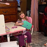 Presley joined the competition — help win amazing prizes! child, girl, smiling, pink_chair, desk, tablet, wooden_dresser, robe, carpet, indoor, home, furniture, toy, footwear, purple_pants, curtains, lamp, book, happy, person