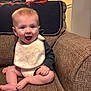 baby, infant, bib, smile, happy, couch, sofa, textile, blanket, living_room, furniture, portrait, sitting, legs, hands, mouth_open, cute, indoor, home, wall_art