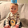 baby, infant, crown, hat, milestone, six_months, onesie, sitting, blanket, textured_blanket, smile, portrait, cheeks, eyes, hands, feet, wooden_sign, indoor, cozy, cute