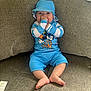 baby, child, blue_outfit, hat, thumb_sucking, couch, sofa, plush_toy, indoor, happy, cute, person, face, feet, clothing, sitting, infant, home, smile, relaxed