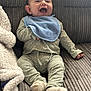 Ezra is registered to the contest to win money with this photo: baby, infant, smiling, laughing, blue_bib, green_outfit, socks, couch, blanket, happy, child, indoor, cozy, cute, person, seated, soft_texture, fabric, home, comfortable