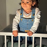 Theo participe au concours pour gagner de l'argent avec cette photo : toddler, child, baby, crib, denim_overalls, sweater_vest, dimples, hands, indoor, soft_lighting, white_crib, cute, portrait, person, baby_clothes, cute_expression, standing, furniture, home, infant