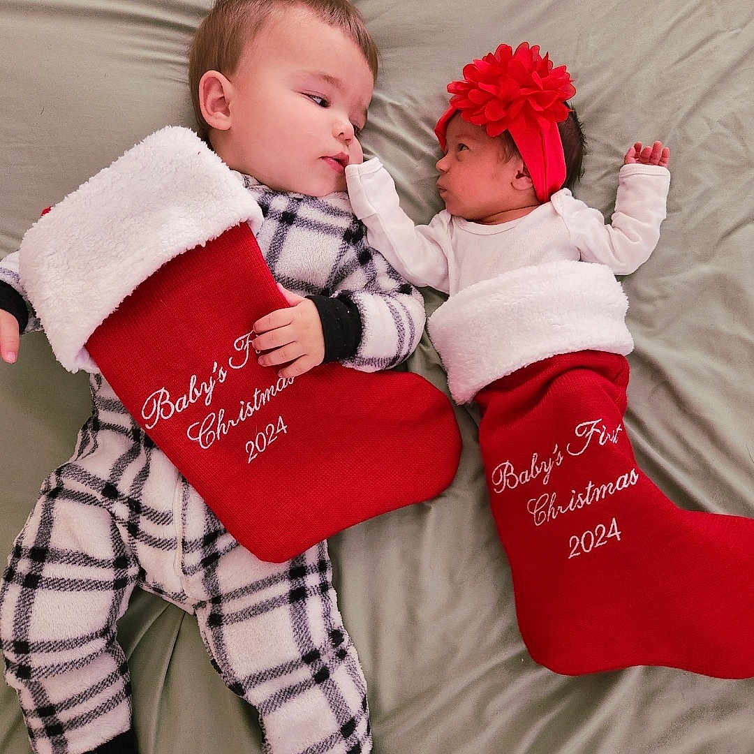Eden And Bram is registered to the contest to win money with this photo: baby, christmas, christmasdecorations, christmasstocking, clothing, couch, cushion, face, festival, furniture, gift, glove, hat, head, hosiery, newborn, person, photography, portrait, stocking