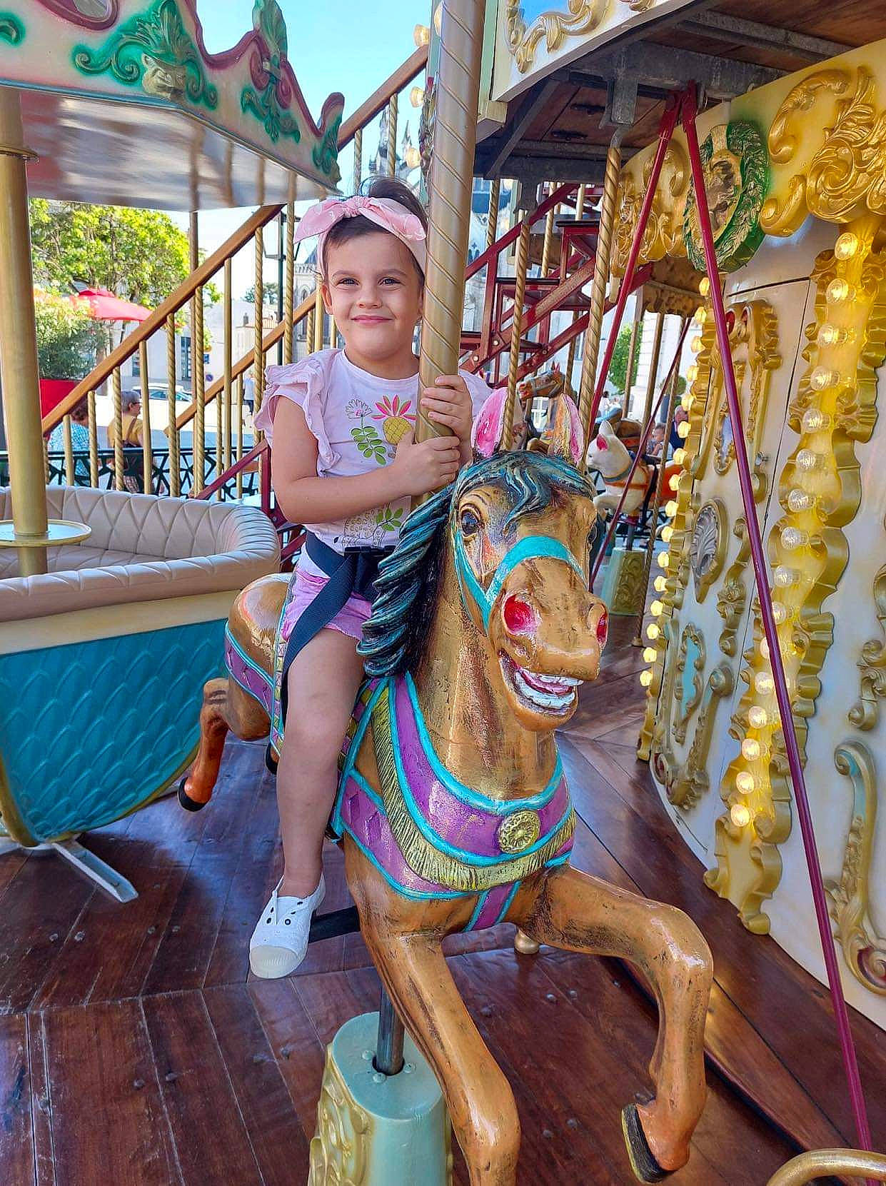 Lyah participe au concours pour gagner de l'argent avec cette photo : amusement_ride, carousel, event, fun, happy, headwear, horse, horse_supplies, horse_tack, joy, landmark, leisure, nonbuilding_structure, person, plant, playground, recreation, sky, smile, toddler
