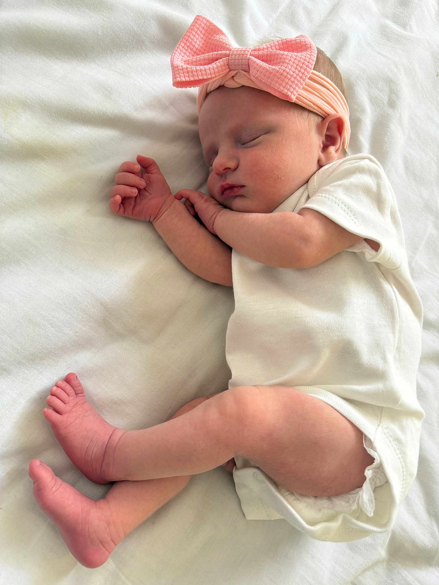 Phoebe is registered to the contest to win money with this photo: baby, sleeping, infant, pink_bow, headband, white_onesie, blanket, soft, cute, peaceful, newborn, skin, foot, hand, sleep, rest, indoors, portrait, child, cozy