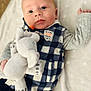 baby, infant, plush_toy, elephant, checkered_vest, blanket, lying_down, cute, child, portrait, soft_toy, blue_eyes, clothing, cozy, indoor, young_child, hand, smile, face, cute_baby