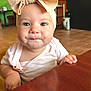 baby, child, headband, bow, face, table, wood, indoor, person, clothing, expression, curious, smile, skin, earring, background, blur, cafe, window, light