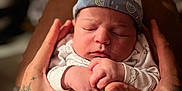 Soann participe au concours pour gagner de l'argent avec cette photo : baby, newborn, sleeping, hands, tattoo, hat, clothing, infant, person, closeup, cute, soft_light, indoor, portrait, peaceful, cozy, skin, human, newborn_clothing, resting