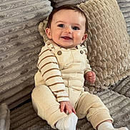 Elio a rejoint le concours — aidez-le/la à gagner de superbes lots ! baby, child, clothing, couch, cozy, cute, happy, home, indoors, infant, overalls, person, pillows, portrait, seated, smiling, sock, soft, striped_shirt, texture