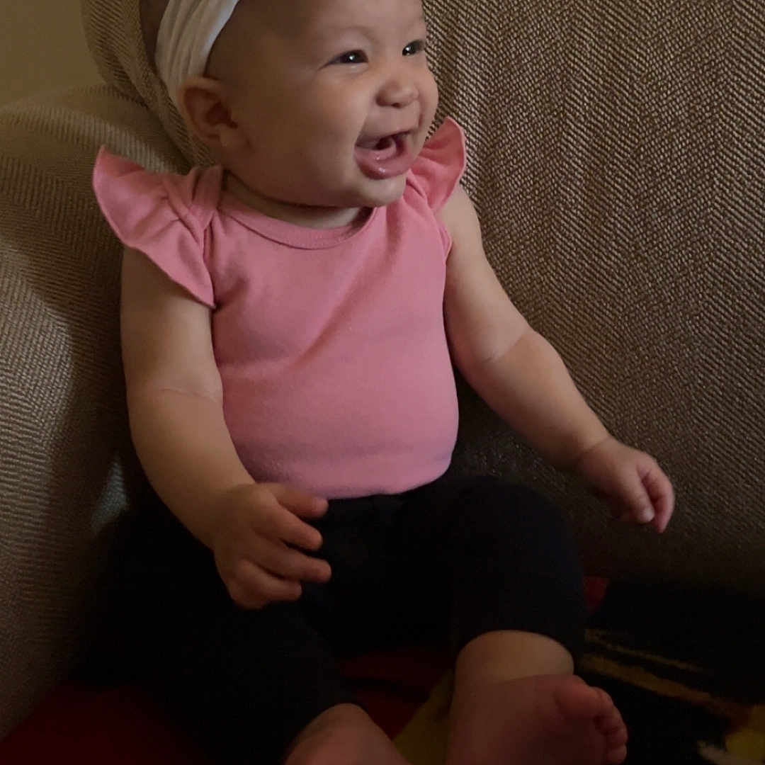 Xahya is registered to the contest to win money with this photo: baby, barefoot, chair, child, cute, face, furniture, happy, head, headband, indoor, infant, one_person, person, pink_clothing, portrait, sitting, smiling, toddler, young_child