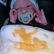 Ryan joined the competition — help win amazing prizes! baby, pacifier, blanket, infant, car_seat, hat, hand, face, child, clothing, cozy, cute, sleepy, newborn, portrait, soft, warm, indoors, young, person