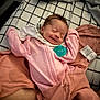 baby, newborn, smiling, pink_pajamas, pacifier, blanket, bedspread, checkered, pillow, soft, sleeping, cozy, infant, cute, child, resting, indoors, person, face, relaxed