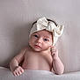 baby, infant, headband, bow, blanket, soft_texture, skin, face, hand, blue_eyes, lying_down, portrait, cute, newborn, child, cozy, innocent, expression, warm, comfortable