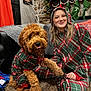 Oakley joined the competition — help win amazing prizes! dog, person, pajamas, plaid, living_room, carpet, stockings, christmas, holiday, decorations, couch, blanket, smiling, pet, fur, indoor, cute, hand_holding, tongue_out, happy