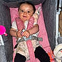 baby, stroller, toy, pacifier, pink, gray, child, happy, smiling, clothing, footwear, sitting, indoor, infant, cute, plush_toy, seatbelt, legs, face, person