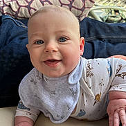 Cameron is registered to the contest to win money with this photo: baby, bib, blue_eyes, child, closeup, clothing, cushion, cute, face, hand, happy, indoor, infant, lying_down, person, pillow, skin, smiling, toy, young