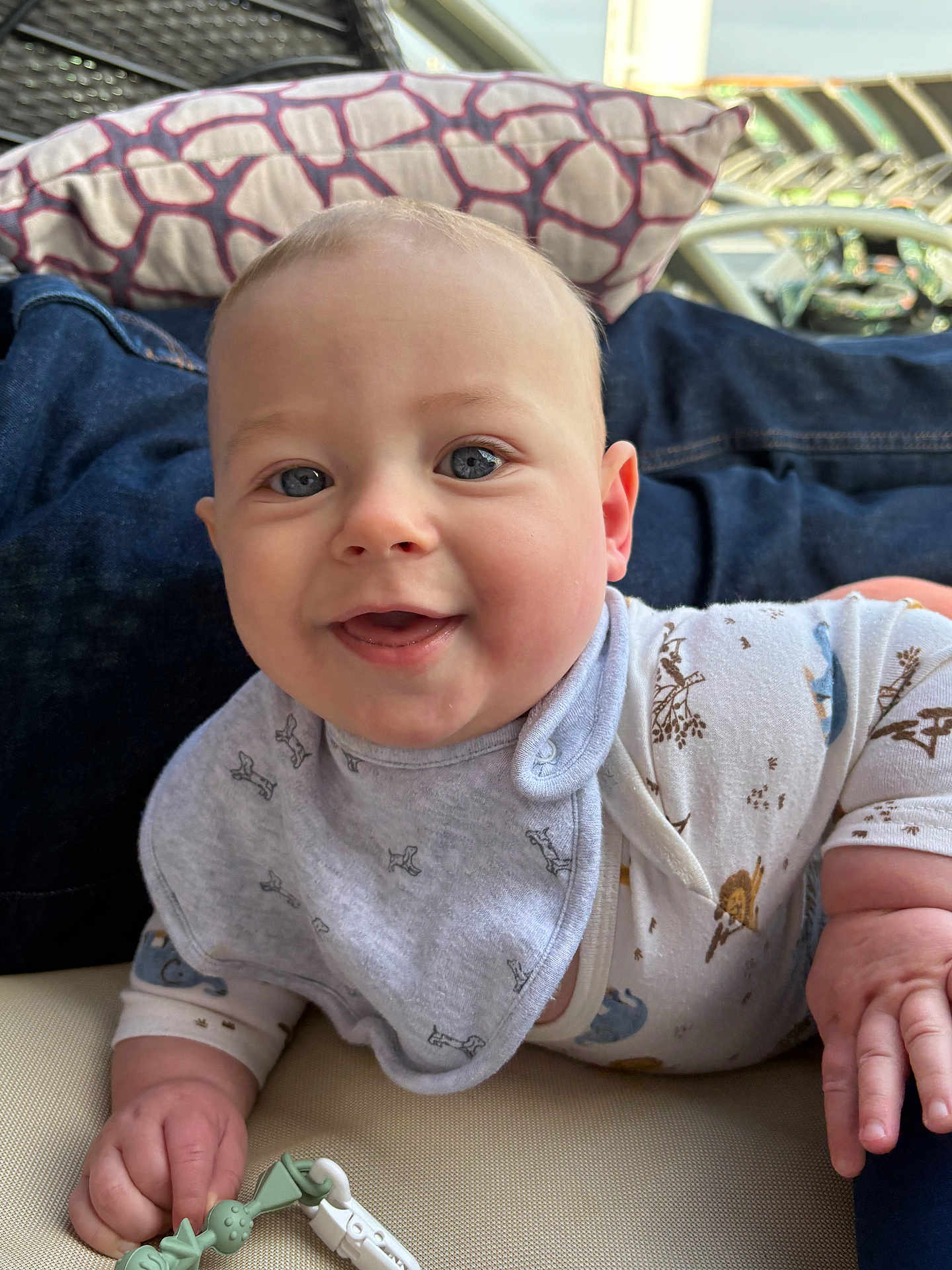 Cameron is registered to the contest to win money with this photo: baby, bib, blue_eyes, child, closeup, clothing, cushion, cute, face, hand, happy, indoor, infant, lying_down, person, pillow, skin, smiling, toy, young