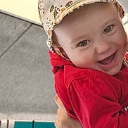 Lucas a rejoint le concours — aidez-le/la à gagner de superbes lots ! apparel, baby, child, cute, expression, eyes, face, hand, happy, hat, headwear, holding, hoodie, indoor, joyful, person, portrait, red_clothing, smiling, young_child