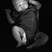 Daniel is registered to the contest to win money with this photo: baby, newborn, sleeping, portrait, black_and_white, infant, onesie, diaper, peaceful, indoors, close_up, face, arms_raised, lying_down, soft_lighting, dark_background, baby_clothing, relaxed, photography, monochrome