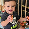 toddler, child, smiling, portrait, sitting, playpen, toys, giraffe_toy, toy_car, indoor, home, baby, happy, short_hair, t_shirt, shorts, play_mat, kneeling, colorful, photograph