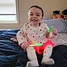 Nova joined the competition — help win amazing prizes! baby, child, smiling, sitting, bed, bedroom, toy, glowing_toy, pajamas, onesie, white_clothing, colorful_pattern, infant, portrait, indoor, window, blanket, pillow, happy, home