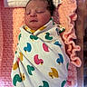 newborn, baby, swaddled, blanket, duck_pattern, sleeping, pink, crocheted, soft, infant, face, head, person, cute, resting, indoors, closeup, wrapped, peaceful, child