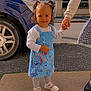 toddler, child, smiling, pigtails, blue_dress, stitch_character, white_shirt, shoes, sidewalk, adult_hand, car, residential_building, windows, daytime, outdoor, happy, person, holding_hands, clothing, cute