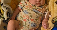 Emery is registered to the contest to win money with this photo: baby, infant, sleeping, blanket, floral_clothing, onesie, portrait, face, cozy, indoor, tablet, screen, technology, lying_down, sitting, barefoot, hands, legs, warm_lighting, home