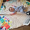 Emery joined the competition — help win amazing prizes! baby, infant, sleeping, onesie, activity_mat, playmat, toys, pacifier, soccer_ball, nursery, floor, indoor, portrait, face, child, colorful, play_area, blanket, lying_down, cozy
