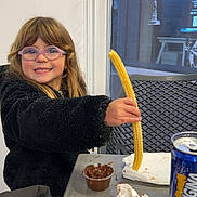 Rose participe au concours pour gagner de l'argent avec cette photo : brown_hair, child, chocolate, churro, drink, food, fork, girl, glasses, hand, happy, indoor, jacket, napkin, orangina, person, seat, smile, snack, table